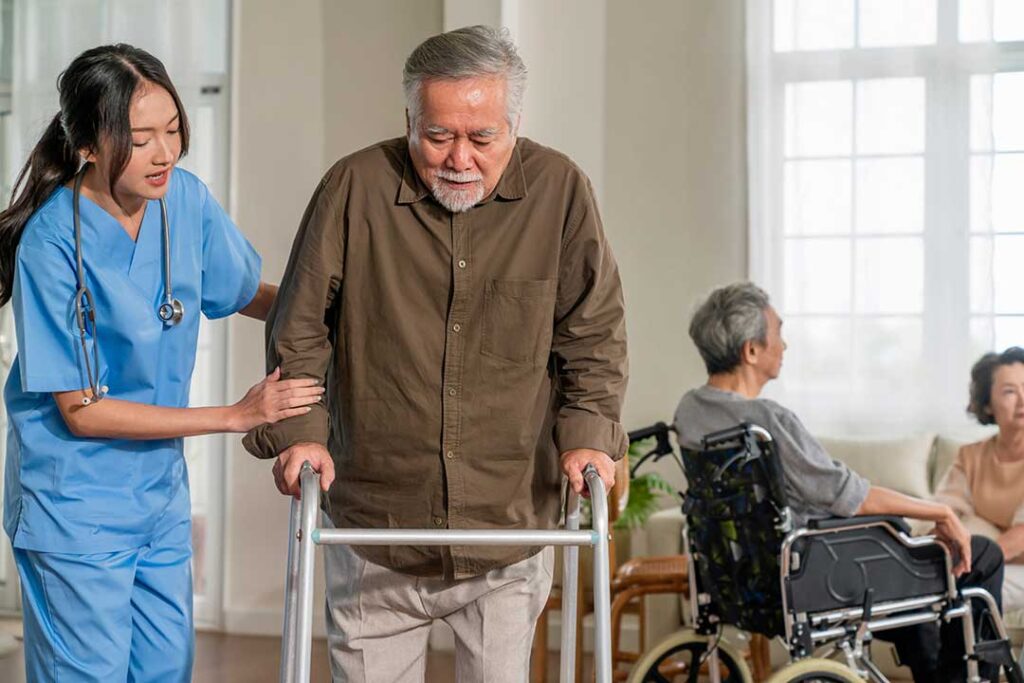 Older LGBTQ+ couple speaking with an assisted living staff member in a bright private room.
