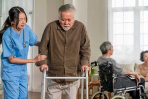 Older LGBTQ+ couple speaking with an assisted living staff member in a bright private room.